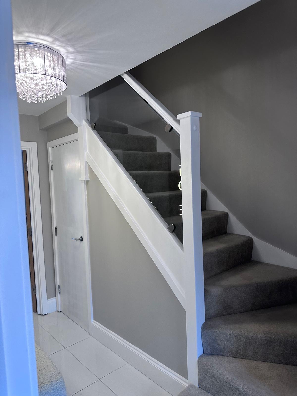 Staircase after renovation, with a glass balustrade and matching newel post