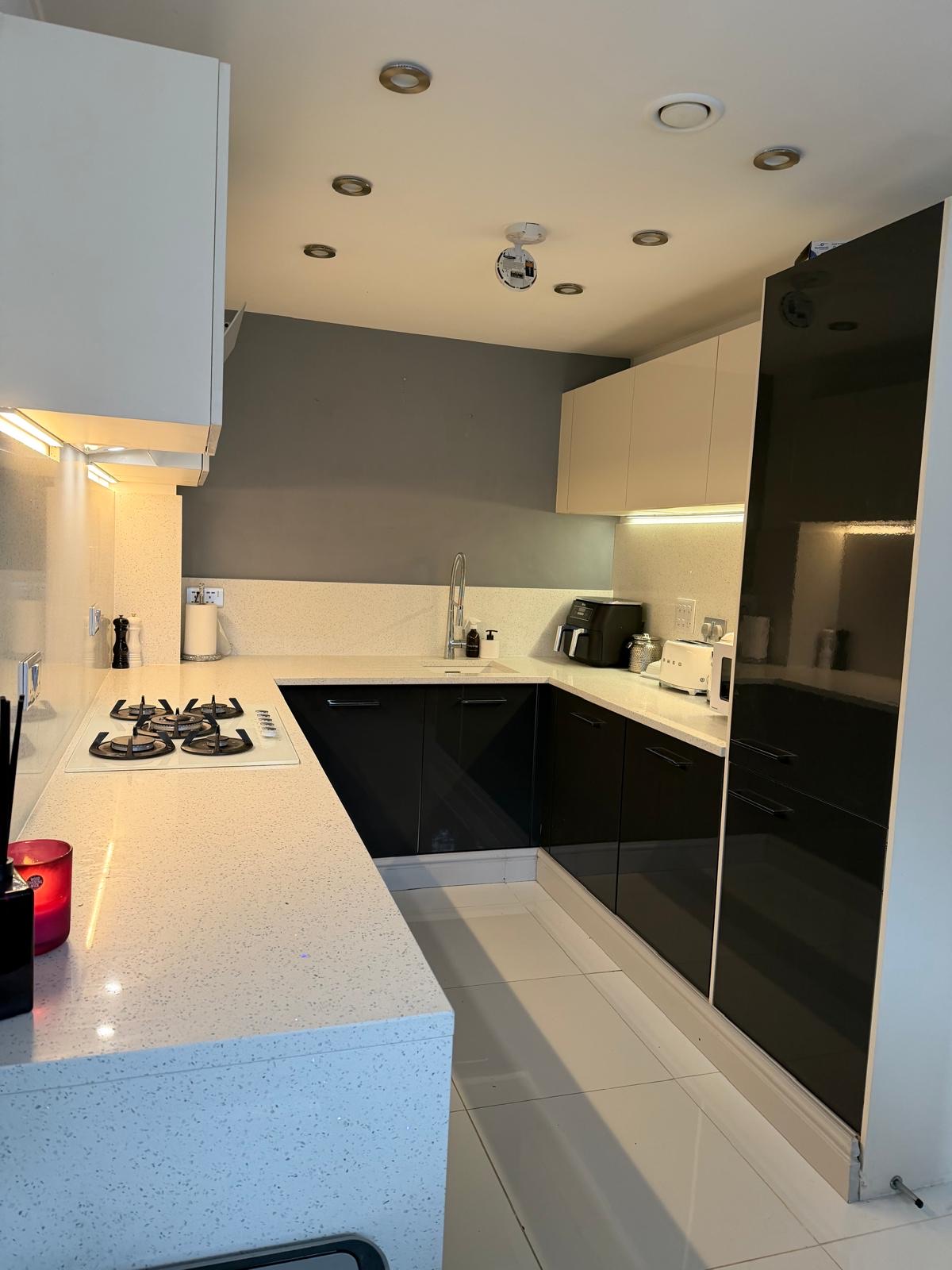 Kitchen sink area before renovation, with black gloss cabinets and tower units
